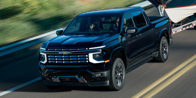 Dark blue Chevy Silverado towing a trailer on a highway.